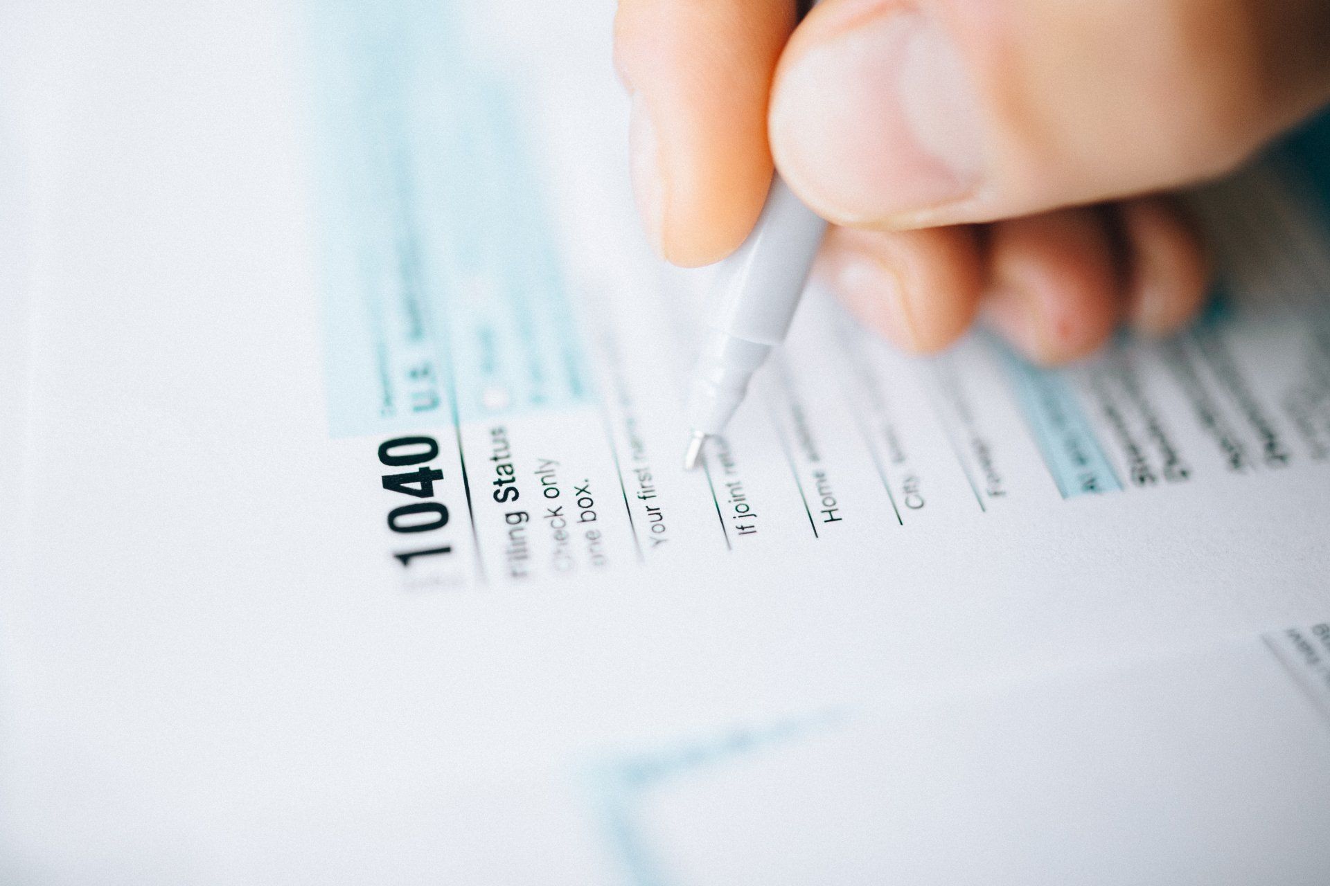 Hand holding a pencil over a financial form or tax document with printed numbers and text